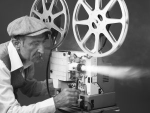 Senior Man Projectionist Starting Film With Old Fashioned Film Projector